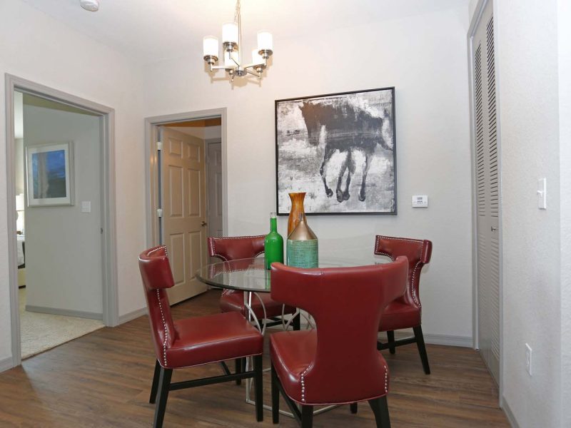 This image shows the Premium Apartment Featuring the dining room area showcasing a light and red combination of colors with minimal pieces of furniture.