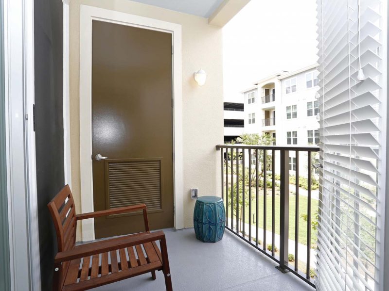 This image shows a private balcony with a wooden chair facing the scenic view outside the apartments.