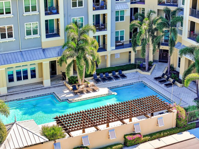 Modern apartment complex with pool, palm trees, and lounge area for luxury outdoor living.