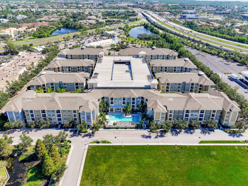 Modern apartment complex with pool, courtyard, and landscaped lawns in suburban community.