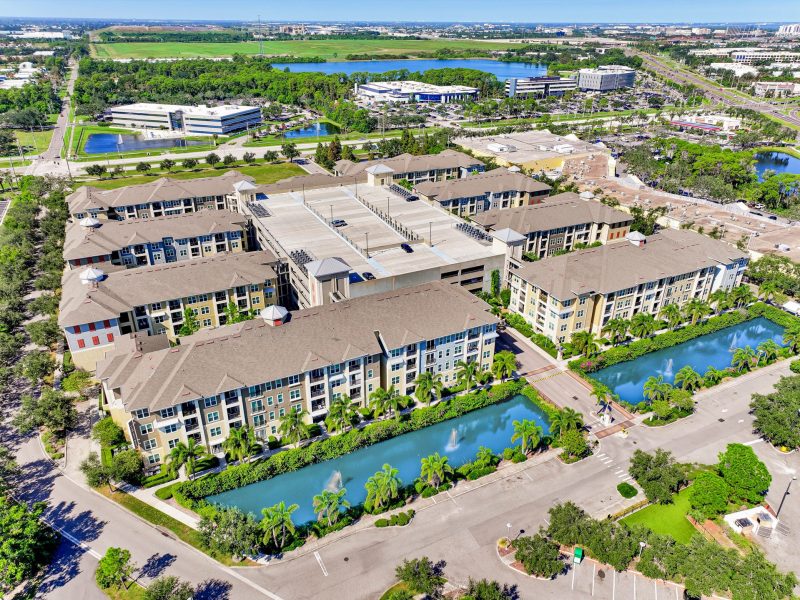 Aerial view of modern residential complex with lakes, greenery, and contemporary apartments.
