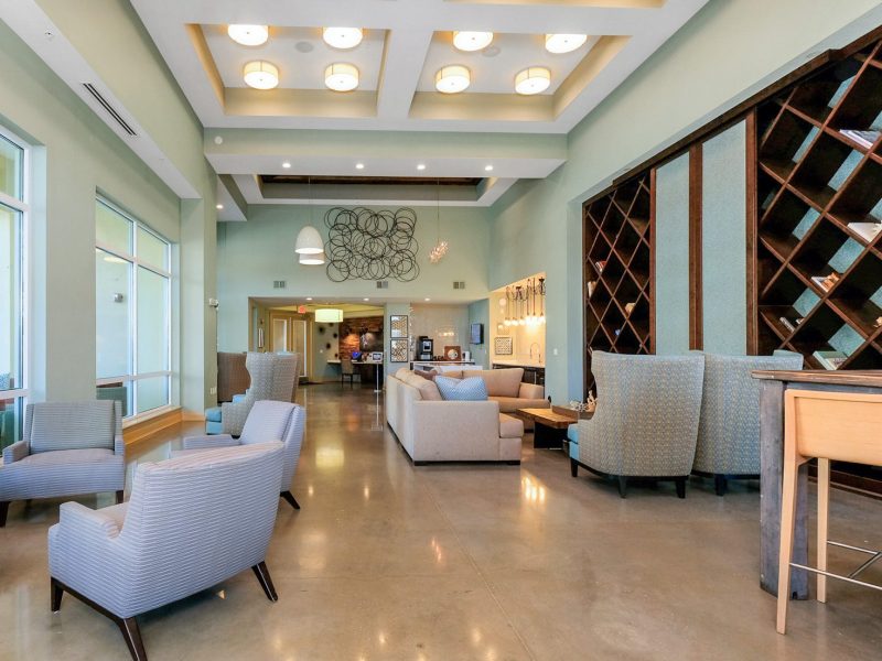 Modern mint green lounge with elegant seating, wine display, and warm natural lighting.