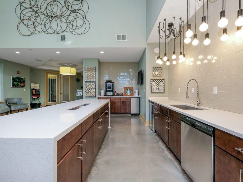 Modern kitchen with white island, wood cabinets, pendant lights, and open concept dining area.
