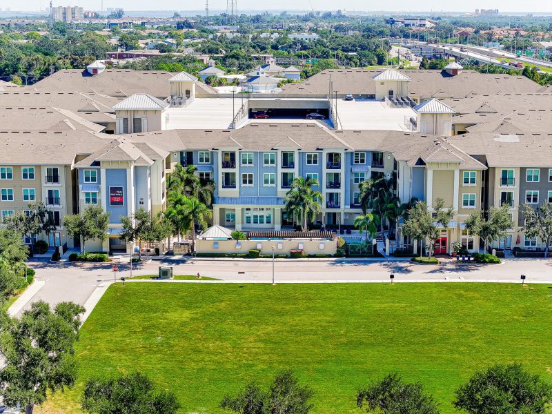 Modern suburban apartment complex with green lawn, balconies, and contemporary architecture.