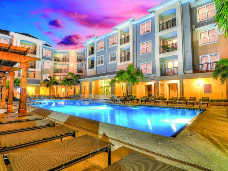 This image shows a view from a night lighted resort-style swimming pool with fountains.