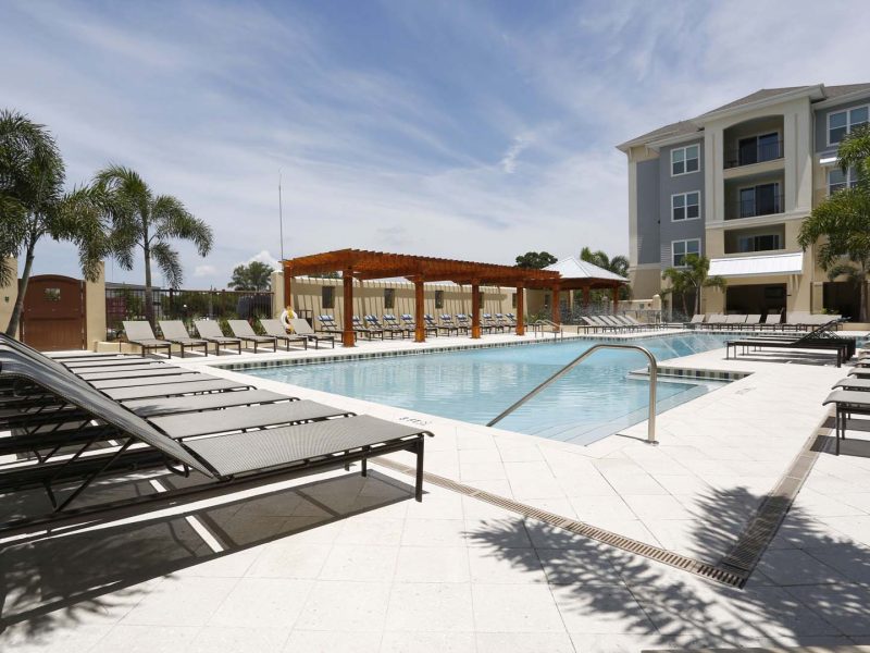 This image shows a view from a daylight resort-style swimming pool with fountains and with a perfect chaise lounge chairs.
