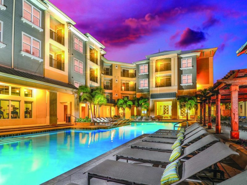 This image shows a view from a night-lighted resort-style swimming pool, with perfect chaise lounge chairs.