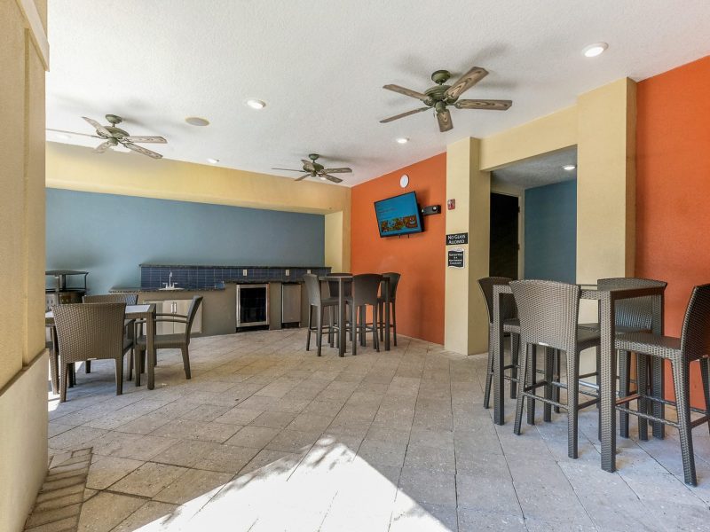 Modern outdoor lounge with colorful walls, high tables, and chairs for social gatherings.