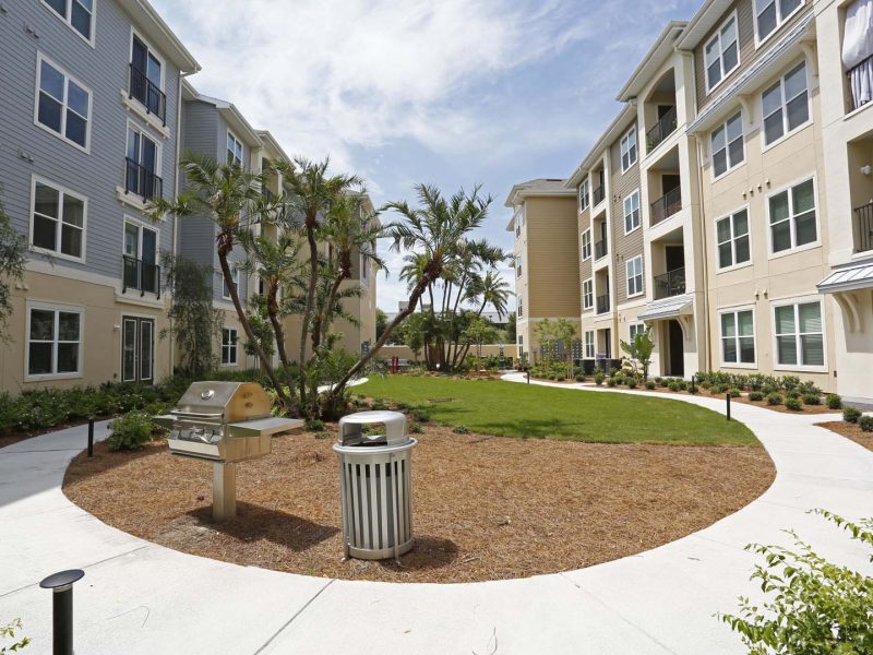 This image shows a community walking trail area featuring the outdoor grilling locations beside the compactor.